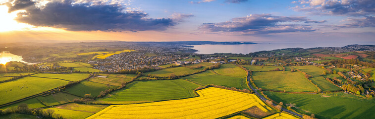 Sunset over Rapeseed fields and Farmlands from a drone, Paignton and Brixham, River Dart, Devon, England