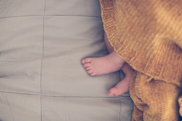 Gentle puffy baby legs on a linen bedspread, top view