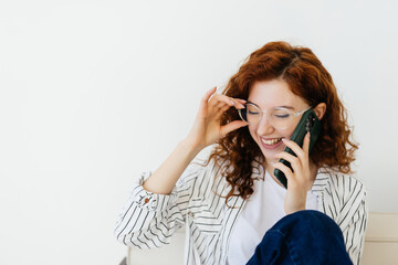 young red hair woman sitting at home sofa couch drinking coffee talking on mobile phone relaxed in communication and lifestyle concept