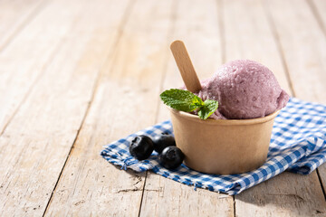 Blueberry ice cream scoop on wooden table. Copy space