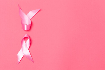 Healthcare Ideas. Flat-lay Image of Two Small Pink Ribbons Against Coral Background as Symbol of Breast  Cancer Awareness During Cancer Fight  Campaign.