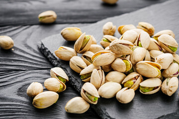 fresh salted pistachios on a black stone wooden rustic background