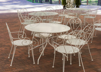 White metallic tables and chairs in summer cafe