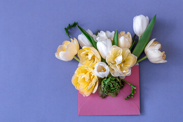 Flowers in an envelope on a colored background, flat lay.