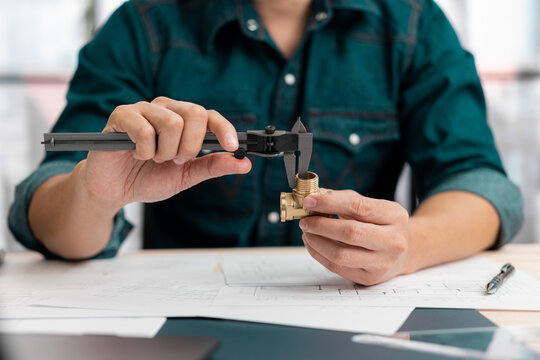 Close up hands of an engineer measures a metal part with Vernier caliper.
