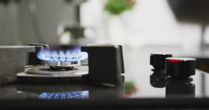 A man's hand ignites a gas burner with electric ignition.