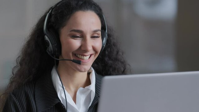 Cheerful young worker business woman girl holding video conference call with client partner wear headphones with microphone provide support service advises customer skilled happy lady working online
