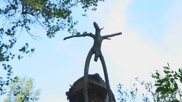 Silhouette wooden snag in the form of a pagan idol against the cloudy sky. Camera zoom in