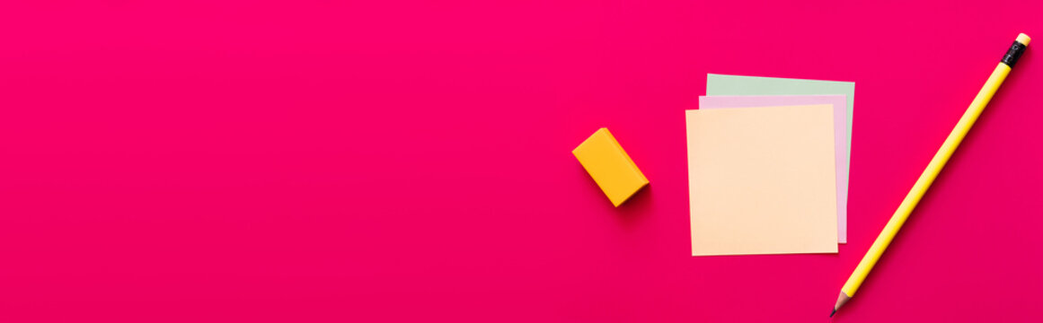 top view of pencil and eraser near multicolored paper notes on pink background, banner.