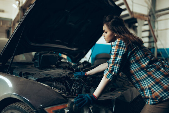 Female auto mechanic, beautiful young girl in working process at auto service station, indoors. Gender equality. Work, occupation, fashion, job