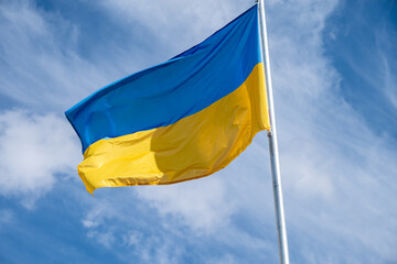 Flag of Ukraine fluttering in the wind on a white cloudy sky day.