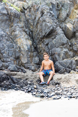 Little kid on a rocky beach at summer