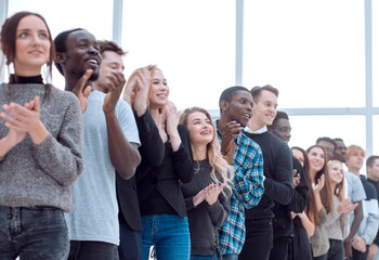 group of diverse young people applaud standing in a row