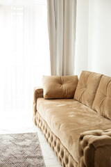 Modern comfortable beige sofa by the window in a stylish living room. Interior design concept.