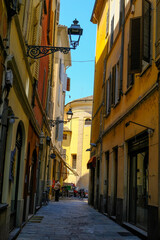 Fototapeta na wymiar Parma, Italy: Old city streets on a sunny day and the cathedral in the back of the street. Travel destinations in Emilia-Romagna