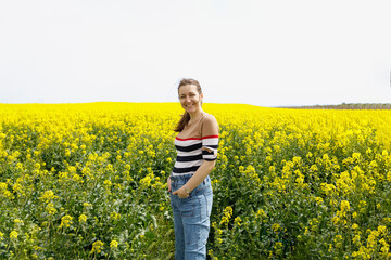 Fototapeta premium Summer portrait of a happy woman standing in a yellow field