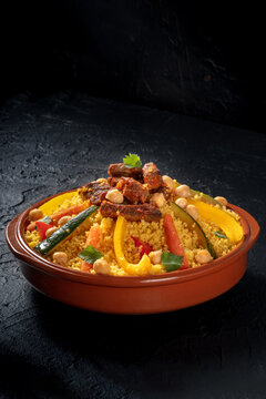 Couscous with meat and vegetables, traditional Arabic food, on a black slate background