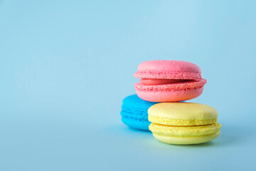Colorful french macarons cookies (macaroons) on blue background. Dessert, vegetarian sweets close up