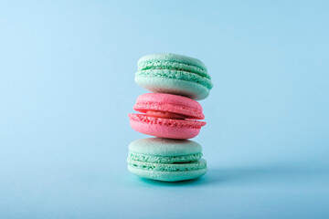 Colorful french macarons cookies (macaroons) on blue background. Dessert, vegetarian sweets close up, stacked balance