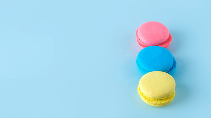 Colorful french macarons cookies (macaroons) on blue background. Dessert, vegetarian sweets close up