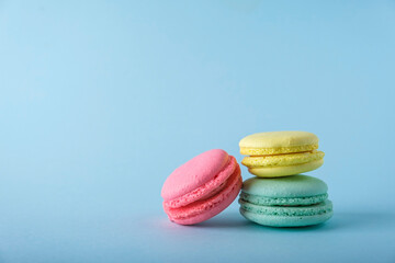 Colorful french macarons cookies (macaroons) on blue background. Dessert, vegetarian sweets close up