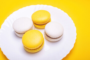 Sweet and bright banana and currant macarons on a white plate. French dessert.