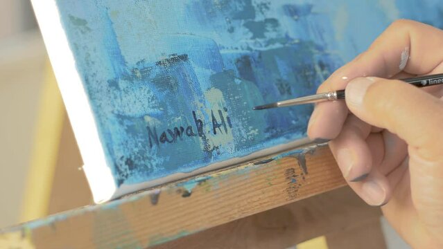 Artist writes signature on completed painting
