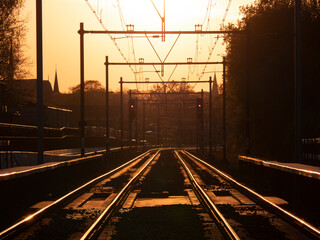 Fototapeta na wymiar Railroad track with beautiful golden sunlight backlight in Hilversum, the Netherlands