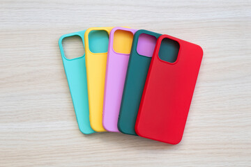 Cases set for smartphone on wooden background. Silicone protection for mobile phone. Colorful...