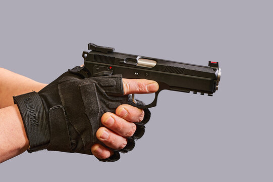 In men's hands, a black pistol on a gray background