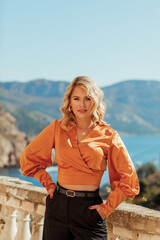 Young beautiful blonde woman in blouse and black trousers on the street