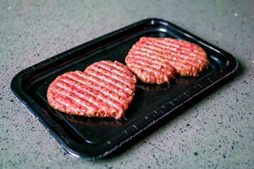 Meat cutlet in the shape of a heart. Vacuum pack of two cutlets. Dinner for lovers on February 14. Meat love. Valentine's Day.