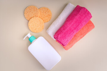 Reusable make-up remover pad and cleansing product in white bottle with dispenser. Multicolor towels. Reusable products for bathroom and skin care.