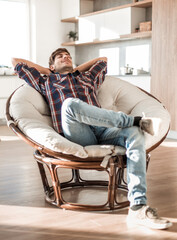 young man dreams of sitting in a chair in his cozy apartment