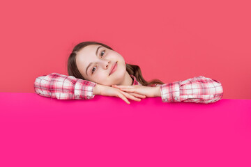 cheerful child behind blank pink paper with copy space for advertisement