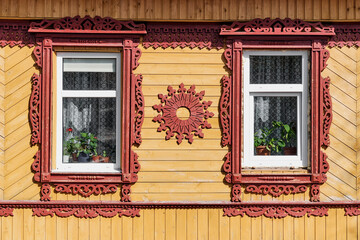 Facade of typical old rural Russian house with carved wooden decorations and architraves. - obrazy, fototapety, plakaty