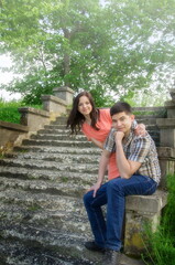 Young couple on stone steps in the park. Man and woman on a background of summer greenery.