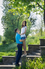 Young couple on stone steps in the park. Man and woman on a background of summer greenery.