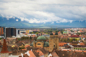 Fototapeta na wymiar Aerial cityscape of historic Sibiu city in Transilvania, Romania, and cloudy Carpathian mountains