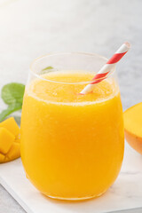 Fresh beautiful delicious mango juice smoothie in a glass cup on gray table background.