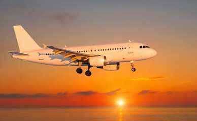 Fototapeta na wymiar Passenger airliner landing over the sea during sunset, side view.
