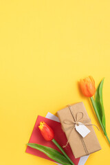 Mother's day background. Top view of gift with tulip bouquet on yellow table background