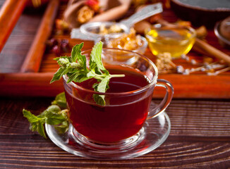 Cup of herbal mint tea with dry herbs on the tray.