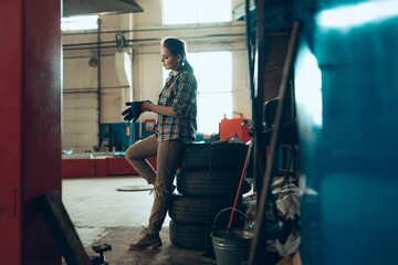 Fototapeta na wymiar Female auto mechanic at auto service station, indoors. Gender equality. Work, occupation, fashion, job