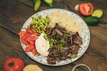 doner or shawarma called pilav ustu on rice, with yogurt , tomatoes and herbs