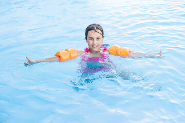 Pretty little girl swimming in outdoor pool and have a fun