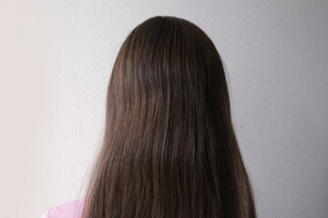 Fototapeta premium european young girl with natural long brown thick hair, stands with her back, rear view, haircut care concept, hair care cosmetics, trichologists research