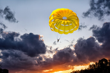 Gliding with a parachute on the background of bright sunset.