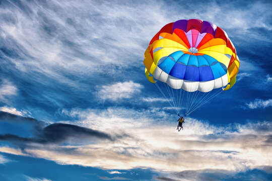 Gliding with a parachute on the background of bright sunset.