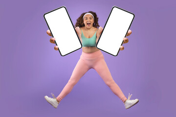 Glad excited young caucasian plus size woman in sportswear jump and freeze in air, show two smartphones